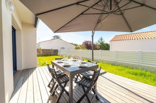 - une table avec des chaises et un parasol sur une terrasse dans l'établissement Maison Familiale avec jardin proche de la mer Parking, à Les Sables-dʼOlonne