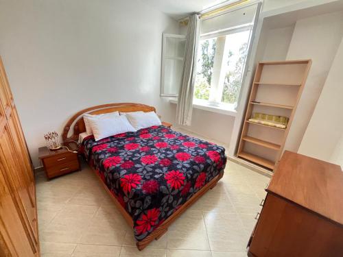 een slaapkamer met een bed met een bloemendeken en een raam bij Casablanca Beautiful and Tranquil Family Apartment in Casablanca