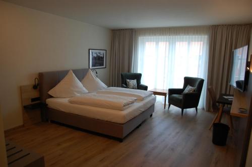 a bedroom with a bed and two chairs and a television at Altstadthotel Millipp in Beilngries