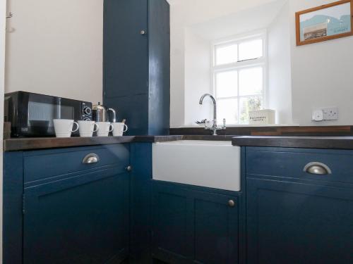 a kitchen with blue cabinets and a sink at Fisherman's Cottage, King Street in Portland