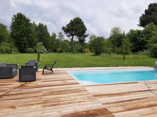 une piscine avec une chaise et un banc sur une terrasse en bois dans l'établissement Maison proche du circuit des 24 heures., à Teloché