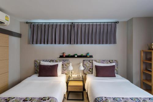 two beds sitting next to each other in a room at Chala Number 2 Art and Gallery in Chiang Mai