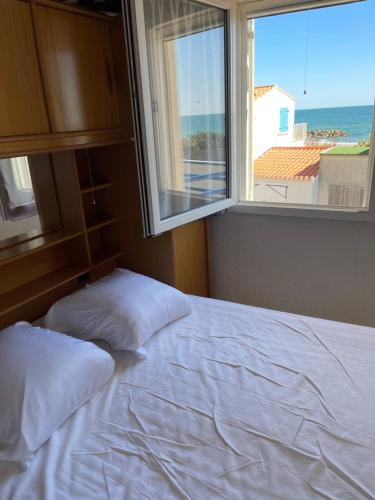 une chambre avec un lit blanc et une fenêtre dans l'établissement La plage, à Frontignan