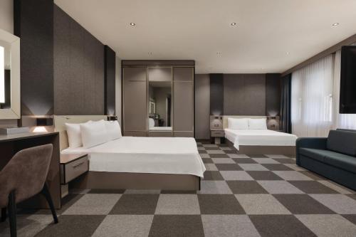 um quarto de hotel com duas camas e um sofá em Tryp By Wyndham Istanbul Sancaktepe em Istambul