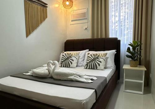 um quarto com uma cama com lençóis brancos e almofadas em Affordable Summer Homes with FREE Pool, Gym and Parking near Puerto Princesa Palawan Airport -T21Kunzite em Puerto Princesa