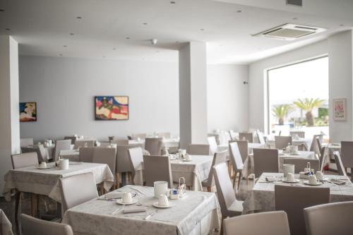 a dining room with white tables and chairs at Hotel Bellavista in Lignano Sabbiadoro