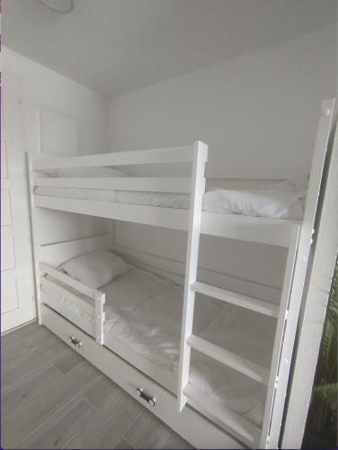 Ce lit superposé blanc se trouve dans une chambre blanche. dans l'établissement Appartement entre Lac et Océan Vieux-Boucau-les-Bains 2 étoiles, à Vieux-Boucau-les-Bains