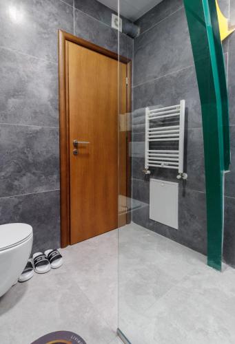 a bathroom with a toilet and a wooden door at Hotel Green Center Gili in Gostivar