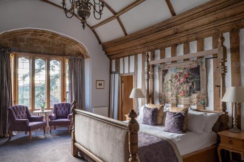 a bedroom with a large bed and two chairs at Fawsley Hall Hotel in Daventry