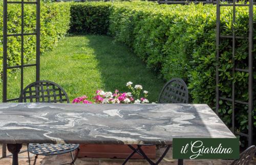 a stone table with chairs and flowers in a garden at Il Borghetto Vacanze nei Mulini in Valeggio sul Mincio