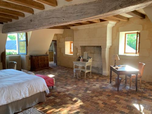 una camera con letto, scrivania e camino di Château de la Faverie chambres d hôtes a Beaumont-Pied-de-Boeuf