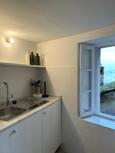 a kitchen with a sink and a window at Le Lampade di Brienno Apartment in Brienno