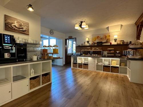 a large kitchen with white cabinets and a wooden floor at Hotel Zartenbach B&B in Hinterzarten