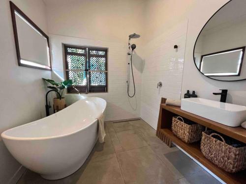 a bathroom with a tub and a sink and a mirror at Bamboo Beach House & Studio in Byron Bay