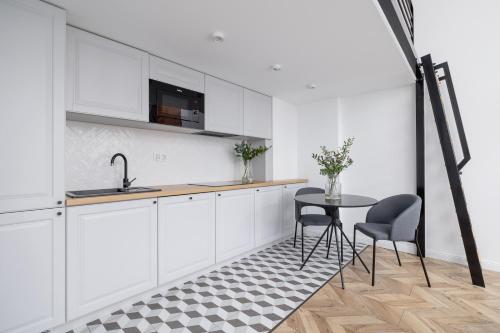 a kitchen with white cabinets and a table and chairs at Apartment with Balcony - Starowiślna 41 in Kraków