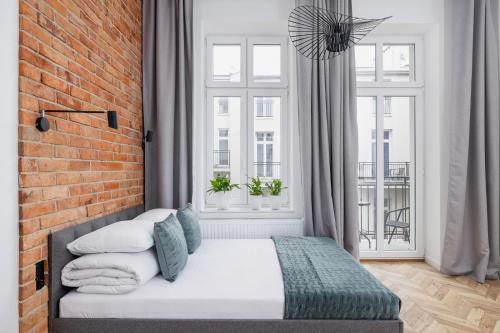 a bedroom with a white bed with a brick wall at Apartment with Balcony - Starowiślna 41 in Kraków