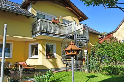 una casa gialla con balcone e lampada di Ferienwohnungen Familie Dinda a Baabe