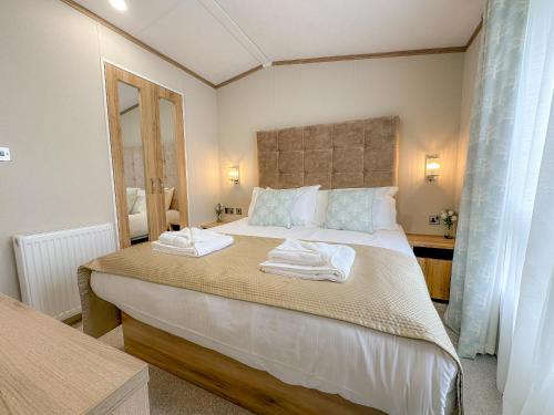 a bedroom with a large bed with towels on it at Serena Holiday Caravan in Bassenthwaite