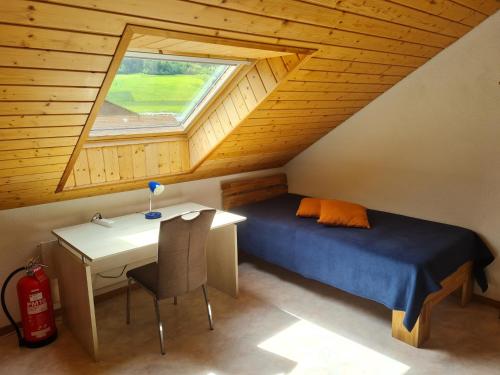 1 dormitorio con cama, escritorio y ventana en Dachwohnung in Welschenrohr, en Welschenrohr