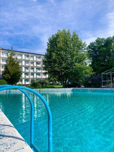 a swimming pool with blue water in front of a building at TOURIST HOTEL in Shymkent