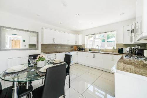 a kitchen with white cabinets and a glass table at COZY 6-Bed Home in Reading, Close to University, Attractions, Train Station with Garden, Parking & WiFi in Reading