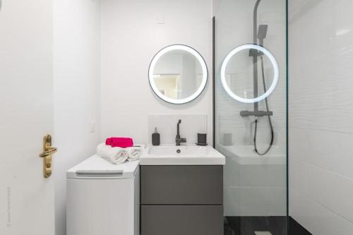 une salle de bain blanche avec un lavabo et un miroir dans l'établissement Appartement moderne pour 6, avec parking et WIFI - Fairytale Factory, à Chessy