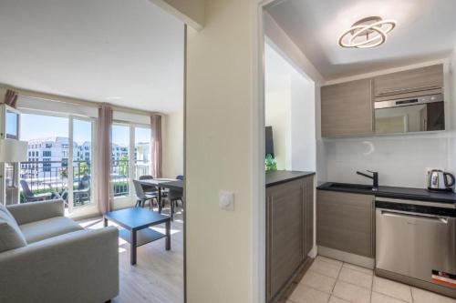 une cuisine et un salon avec un canapé et une table dans l'établissement Appartement moderne pour 6, avec parking et WIFI - Fairytale Factory, à Chessy