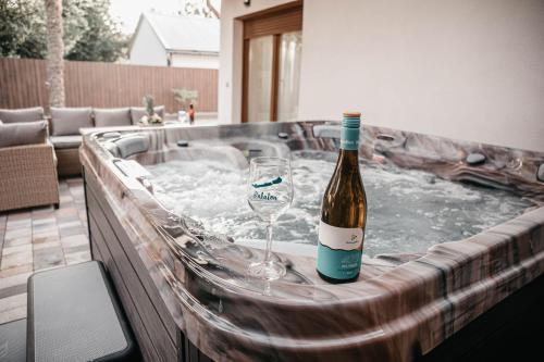 a bottle of wine and a wine glass in a hot tub at Luxury Wellness Home II. Balatonboglár in Balatonboglár