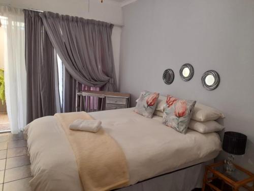 a bedroom with a bed with pillows and clocks on the wall at Ukarimu Guest House in Klerksdorp