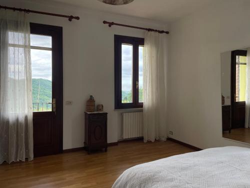 a bedroom with white walls and a bed and windows at Silvia Miotto's Guesthouse in Guia