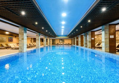 a large swimming pool in a building with a large pool at Grand Royale Apartment Complex & Spa in Bansko