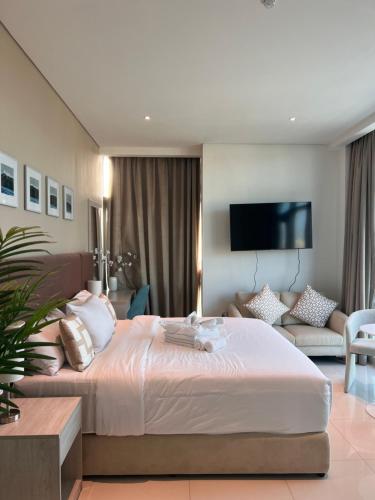 een slaapkamer met een groot bed en een woonkamer bij Serenity Suites studio in Seven Palm corner view in Dubai