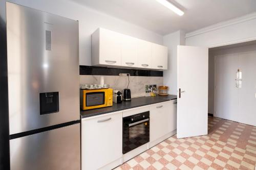 une cuisine avec des placards blancs et un four micro-ondes jaune dans l'établissement Jolie appartement à 10 minutes de la gare de Marseille, à Marseille