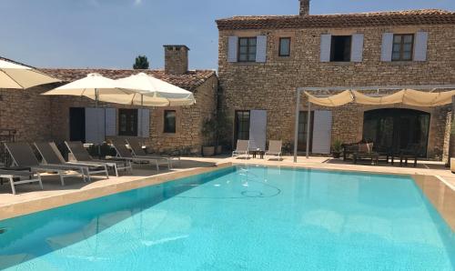 - une piscine avec des chaises et des parasols à côté d'un bâtiment dans l'établissement Villa Helios, à Rustrel