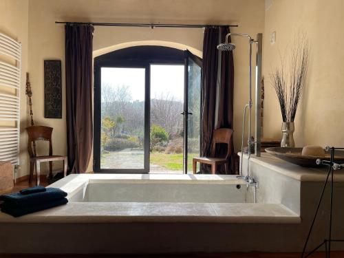 une grande baignoire dans une salle de bain avec une fenêtre dans l'établissement Villa Helios, à Rustrel
