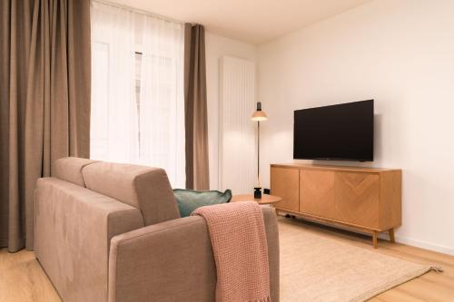 a living room with a couch and a flat screen tv at Limehome Vienna Favoritenstr in Vienna