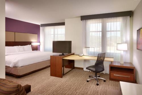 a hotel room with a bed and a desk with a computer at Residence Inn by Marriott Flagstaff in Flagstaff
