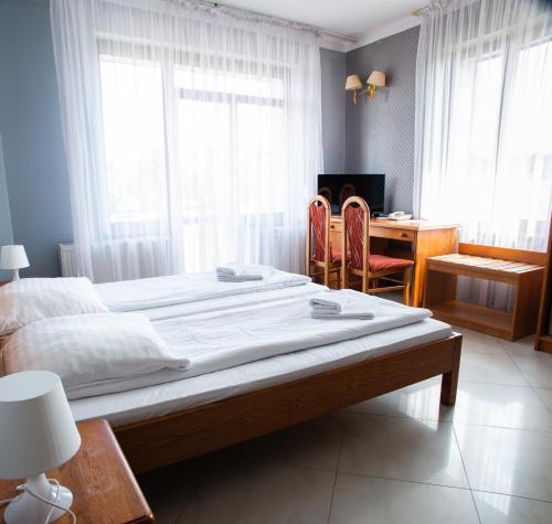 a bedroom with a large bed with a desk and a table at Perła in Leszno