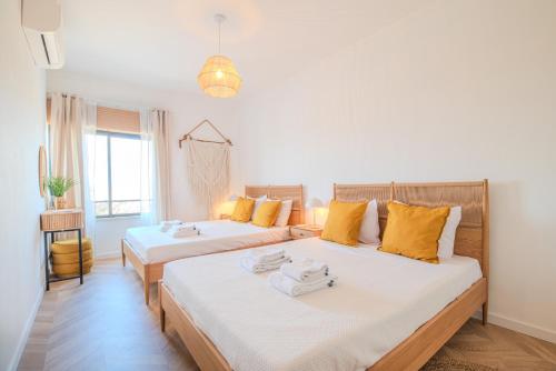 um quarto com 2 camas e almofadas amarelas em Casa de Cotton by MOJE Holiday em Portimão