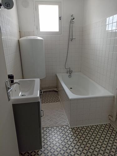 Baño blanco con bañera y lavamanos en Appartement Auzances, en Auzances