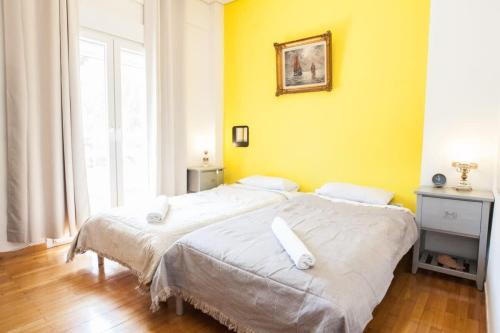 two beds in a room with a yellow wall at Amazing apartment at Exarcheia in Athens