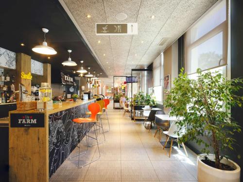 een restaurant met een bar met oranje krukken bij Ibis Sevilla in Sevilla