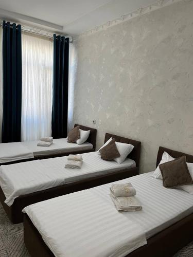 two twin beds in a room with a window at Hotel Life in Aktepa-Chigatay
