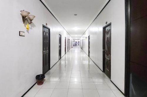 an empty hallway with black doors and white tile floors at Hotel Tanjung Pinang Jaya RedPartner in Tanjung Pinang 