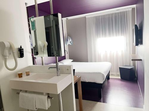 a bathroom with a sink and a bed with a mirror at ibis Styles Nimes Gare Centre in Nîmes
