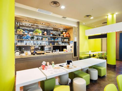 un restaurant avec des tables blanches et des chaises vertes dans l'établissement Ibis Budget Sevilla Aeropuerto, à Séville