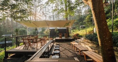a patio with a tent and wooden tables and chairs at Bobocabin Pacet, Mojokerto in Claket