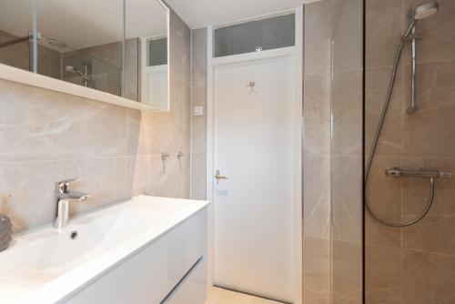 a bathroom with a white sink and a shower at Family Home Michelle in Zandvoort