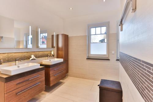 La salle de bains est pourvue de 2 lavabos et d'un miroir. dans l'établissement Landhaus Wreechen mit Sauna, à Putbus