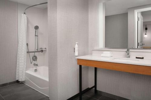 uma casa de banho com um lavatório, uma banheira e um espelho. em Embassy Suites La Quinta Hotel & Spa em La Quinta